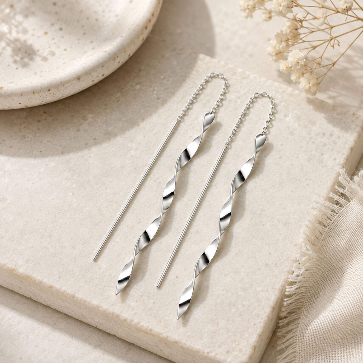 Flat lay of long spiral twist sterling silver threader earrings