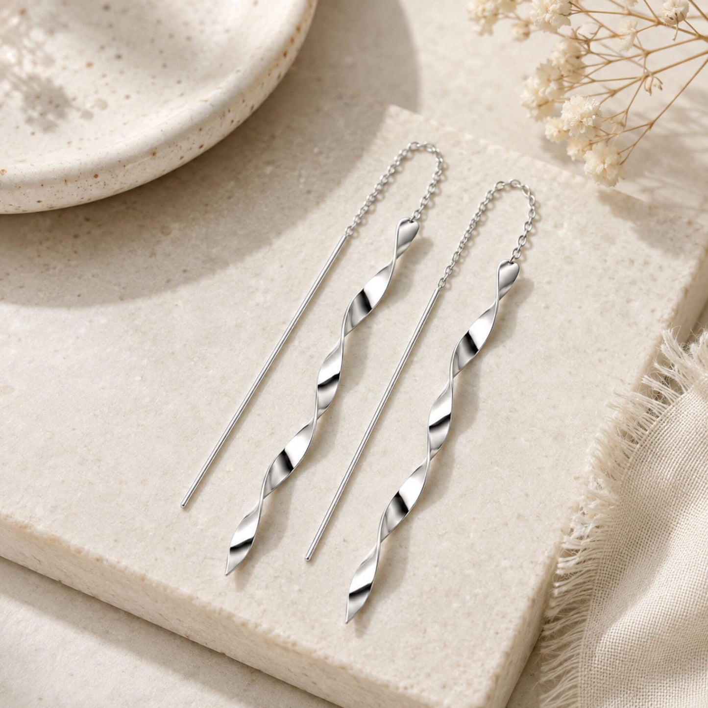 Flat lay of long spiral twist sterling silver threader earrings