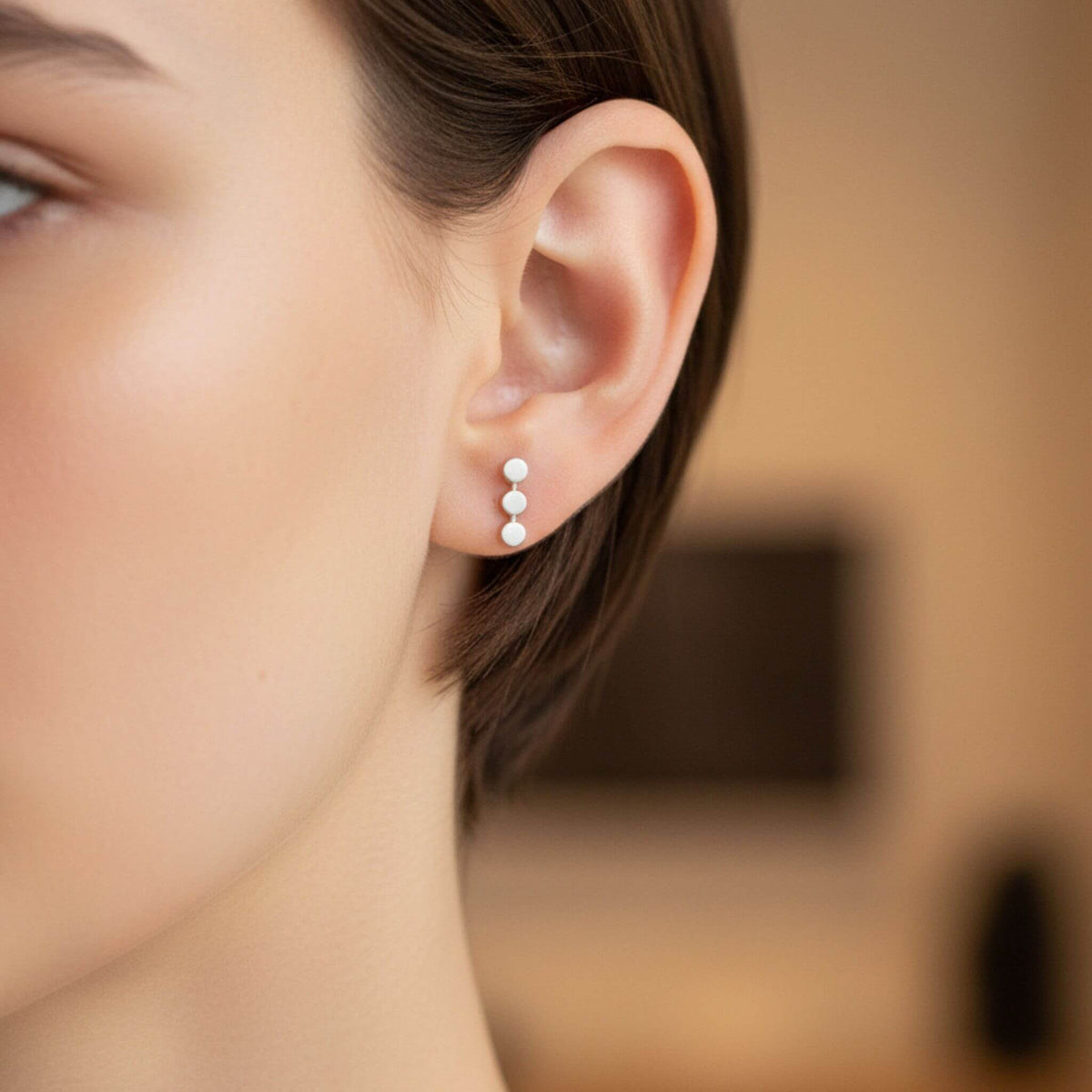 Sterling silver three dot stud earrings worn on ear