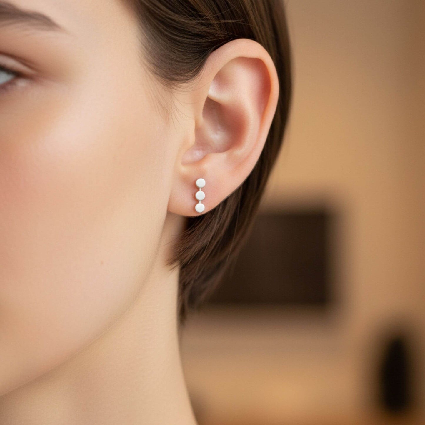 Sterling silver three dot stud earrings worn on ear