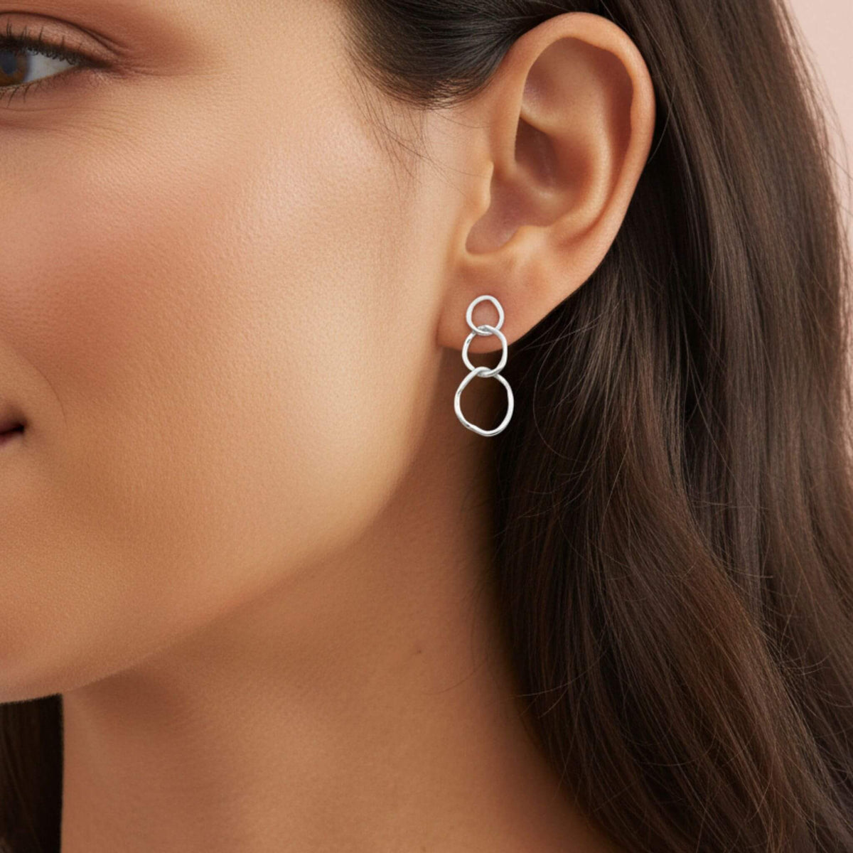 Close-up of sterling silver triple circle drop earrings on ear