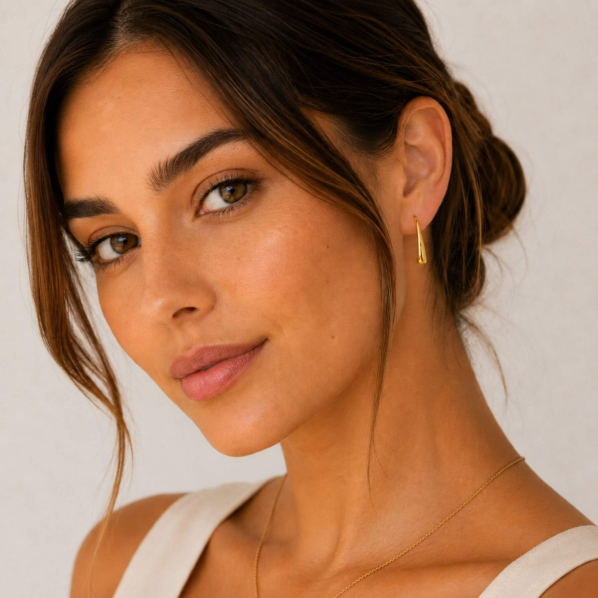 Model wearing 18K gold plated stainless steel teardrop hook earrings for women. Lightweight hypoallergenic teardrop hook earrings for everyday wear.