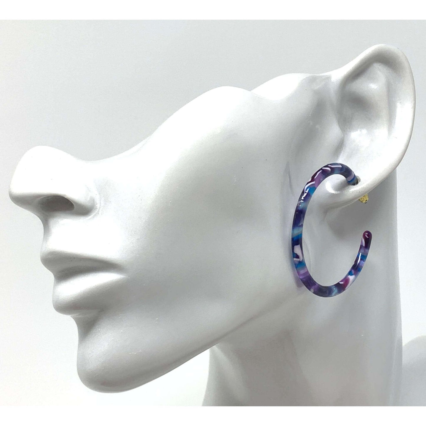A pair of large, dainty resin hoop earrings with a purple & blue marbled design