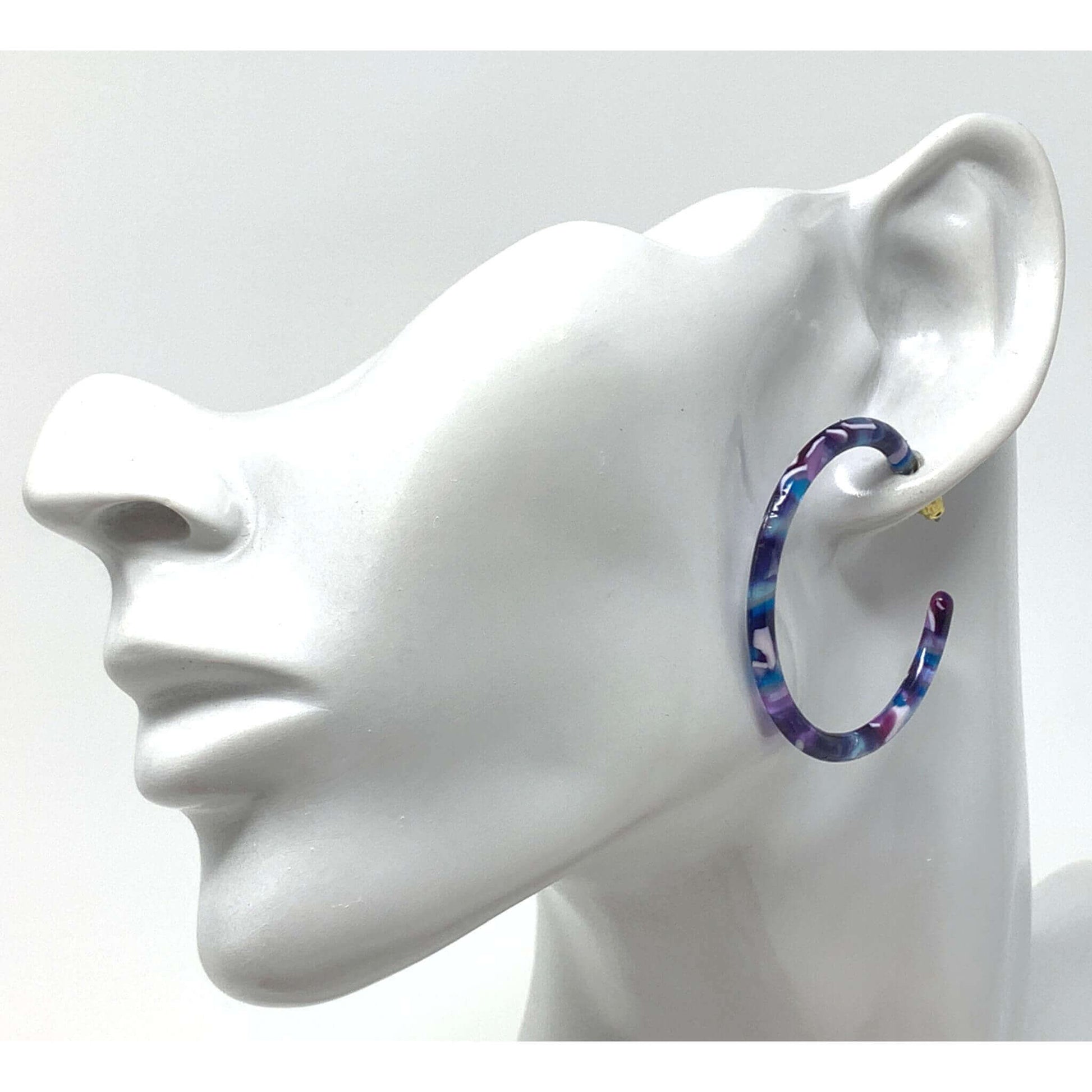 A pair of large, dainty resin hoop earrings with a purple & blue marbled design