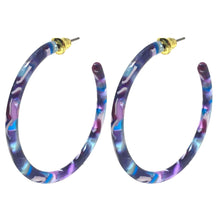 A pair of large, statement resin hoop earrings with a beautiful purple and blue marbled design.
