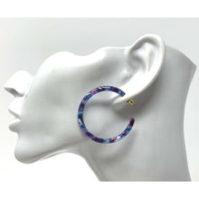 A pair of statement resin hoop earrings with a bold and eye-catching design
